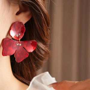 Detail view of red marble resin flower earrings with crystals on model's ear