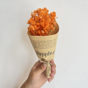 Close-up of mini orange dried baby's breath bouquet wrapped in vintage newsprint paper