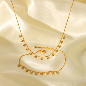 Elegant gold beaded stainless steel necklace with round white zircons on beige silk background