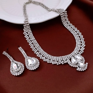 Macro shot of silver-tone teardrop rhinestone necklace and matching earrings on red silk
