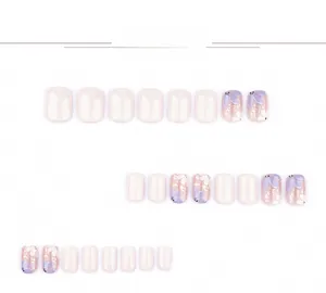 Macro shot of press-on nails featuring hand-painted purple floral patterns and gold foil flakes