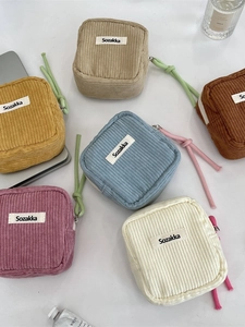 Modern corduroy cosmetic bags in various colors on a white desk with lifestyle items