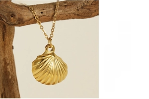 Detail of a golden shell pendant necklace displayed on a natural wood branch