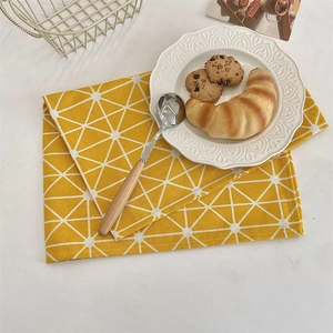 Detail of yellow cotton linen placemat with white star pattern on dining table