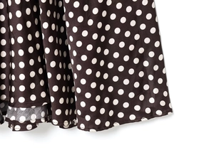 Gros plan détaillé montrant les coutures de qualité sur l'ourlet de la robe à pois