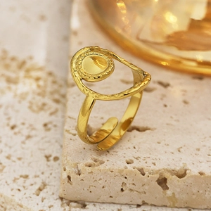 Elegant gold adjustable ring with hammered texture and round top on beige stone pedestal