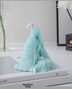 Detailed blue candle featuring a girl carving, placed on white books for decor