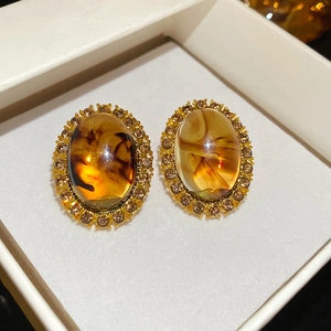 Close-up of vintage gold oval earrings with amber resin and sparkling rhinestones