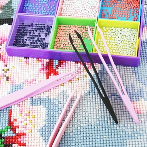 Diamond painting kit with four nylon tweezers and a purple bead tray on floral canvas