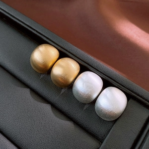 Gros plan de boucles d'oreilles géométriques mates en or et argent sur support cuir