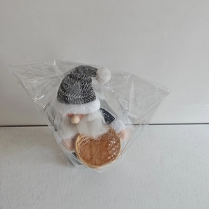 Close-up of a Nordic Christmas gnome in grey knitted hat packed in a clear bag