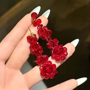 Boucles d'oreilles pendantes fleurs en cristal rouge avec clou en or sur fond sombre