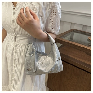 Detail of silver metallic handbag with butterfly accents and pleated texture
