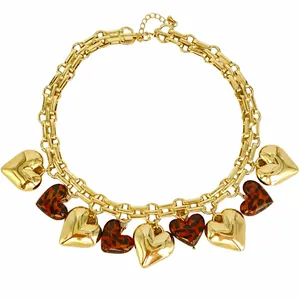 Dettaglio di una collana a catena dorata con ciondoli a cuore leopardati e semplici.