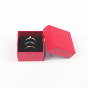 Detail view of red diamond pattern jewelry box storing golden rings with blue and white stones