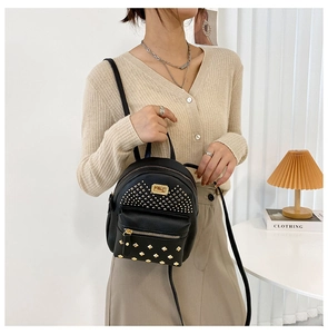 Detail of a black mini backpack with gold rivets and dual zipper compartments