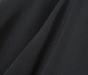 Gros plan du tissu satiné noir montrant la texture lisse et les reflets élégants