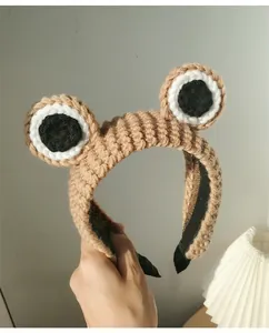 Close-up of khaki knitted frog headband with large eyes and black non-slip lining