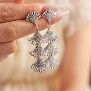 Close-up of sparkling silver fan-shaped tassel earrings with rhinestones on a model