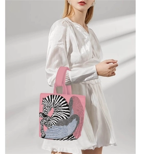 Detail of pink Van Gogh style bucket bag with zebra print held by a model in a white dress