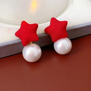 Macro detail of red fabric star and white pearl earrings for a sweet elegant look