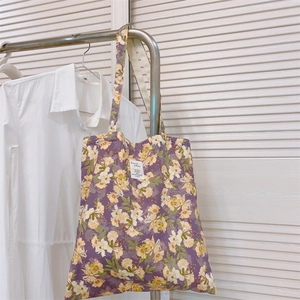 Vista dettagliata della borsa tote in tela a fiori viola scuro appesa in casa