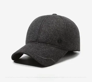 Detail view of dark grey wool blend baseball cap with ear flaps and round side logo