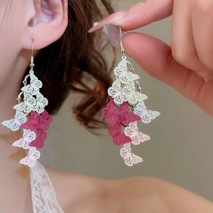 Close-up of elegant gradient pink butterfly tassel earrings worn by a model