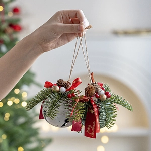 Weihnachtsglocken Ornamente mit roter Schleife Tannennadeln und Beeren in der Hand