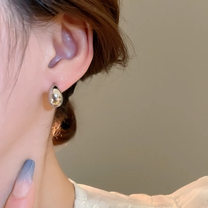 Close-up of polished silver teardrop earrings for women on model ear with glossy finish