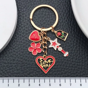 Red heart and rose magic wand keychain set with enamel charms on black leather background