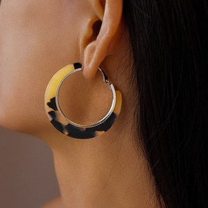 Gros plan d'un mannequin portant des boucles d'oreilles créoles à motif léopard et métal