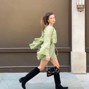 Green high-waist chiffon dress with tiered ruffles and flared sleeves, paired with black boots
