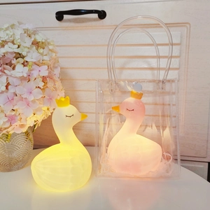 Swan-shaped LED night lights with golden crowns in a transparent gift bag display