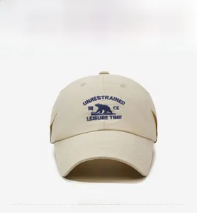 Detailed blue embroidery of a bear silhouette and lettering on a beige baseball cap