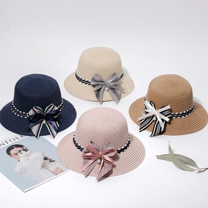 Close-up of four woven sun hats in navy, beige, khaki, and pink with pearl ribbon bows