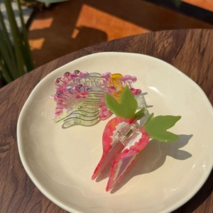 Vue détaillée de la pince à cheveux fraise en acétate rose avec feuille verte et strass