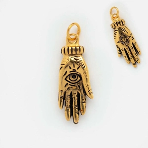 Close-up of gold palm pendants with eye symbols and colorful zircon accents for DIY jewelry