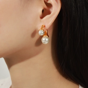 Eleganti orecchini a doppia perla dorati con design geometrico minimalista indossati