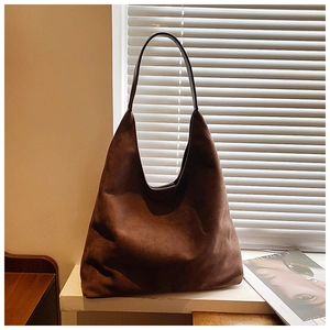 Detailed texture of a large dark brown suede tote bag in natural window light setting