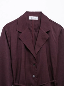 Close-up of brand label and size tag on a dark burgundy satin shirt for women