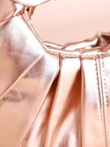Detailed macro view of metallic rose gold pleated leather and fine stitching of the clutch