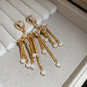 Boucles d'oreilles fleuries dorées avec pampilles et perles sur écrin en velours