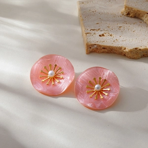 Detailed close-up of pink resin flower stud earrings with golden stamens and white pearls