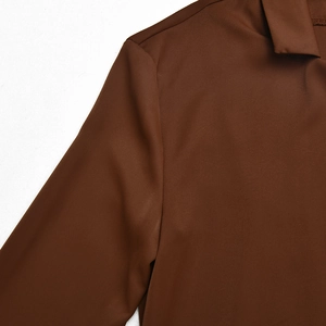 Detailed close-up of brown lapel collar and shoulder seam on soft polyester fabric