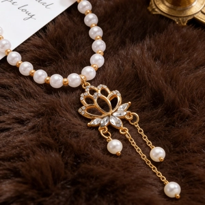 Close-up of a gold lotus pendant with sparkling gems and pearls on dark luxury fur