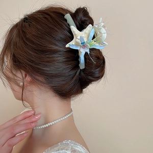 Detailed view of starfish and fabric flower hair clip styled on a woman's hair bun