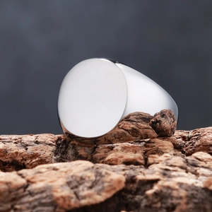 Close-up of polished silver stainless steel signet ring displayed on rustic wood bark