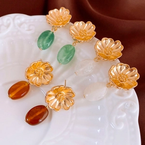 Vintage floral drop earrings in green, white, and amber resin on an elegant white plate