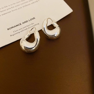 Detailed close-up of polished silver multi-layer earrings on a brown matte surface